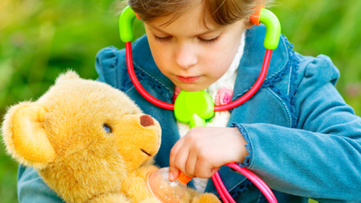 Image of a child examining a toy bear with a toy stethoscope